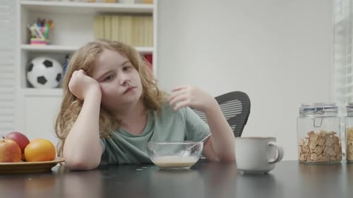 Tired Child Eating Breakfast at the Table
