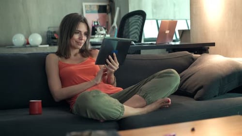 Woman using tablet sitting on couch at home