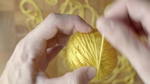 Close up of hand winding ball of wool. Static. Blur background. Top view