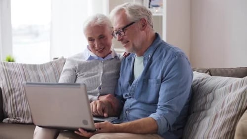 Senior Couple Video Calling on Laptop from Sofa