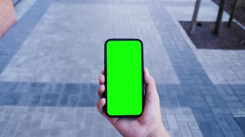 Person Hold In Hand Smartphone With Green Screen Chroma Key And Talking Of Video Call. Young Adul...