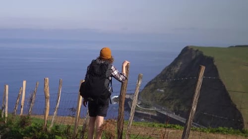 Male hiking backpacking hiker man looking into distance to ocean cliff