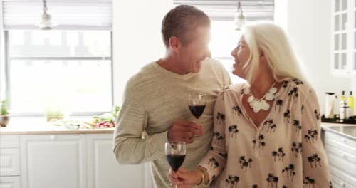 Senior Couple Drinking Wine and Talking in Kitchen