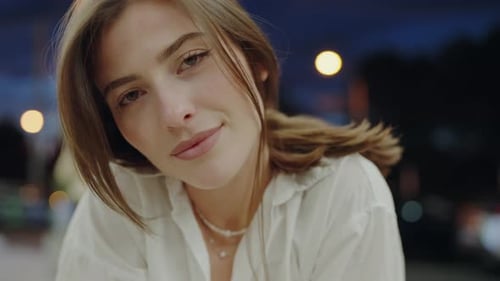 Charmante Frau sitzt am Cafétisch und schaut mit flirtendem Blick in die Kamera