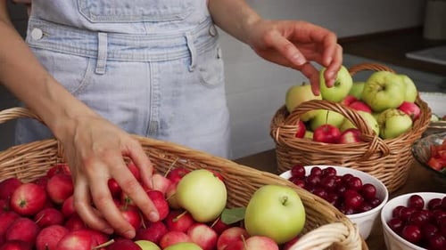 Woman's Hands Separating Paradise and Green Apples From Wicker Baskets Cherries Nearby on Wooden