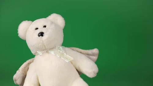 Stuffed and fluffy teddy bear toys with angel wings playing and dancing on a green background.