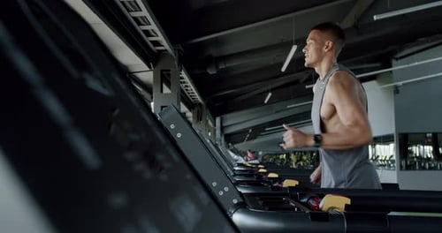 Sporty Guy with Muscular Body Exercising at Modern Gym and Running on Treadmill