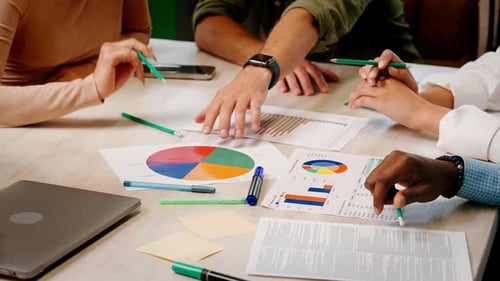 Business Team Discusses Charts on Papers with Statistics