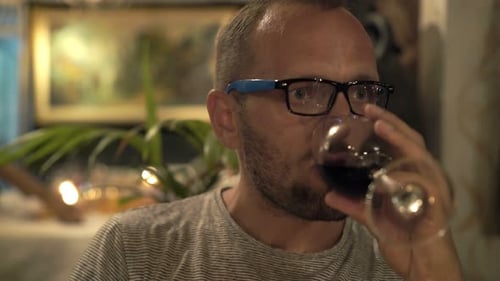 Sad, Unhappy Man Drinking Wine Sitting in Cafe at Night 30s