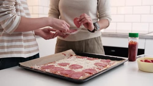 Teen and Adult Making Pizza in a Kitchen