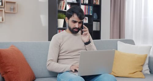 Young Adult Using Laptop and Talking on Phone