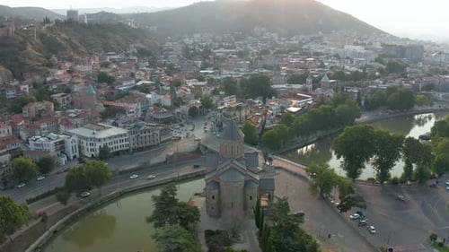 Aerial view of Metekhi church in downtown Tbilisi, Georgia at sunset, sunrise with mountains in the