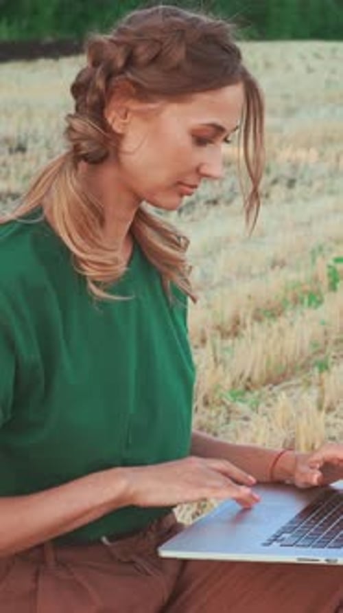 Woman Using Laptop on Agricultural Field