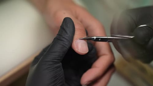 Closeup Top View of Unrecognizable Manicurist Female Wearing Black Gloves Removing Cuticle Using