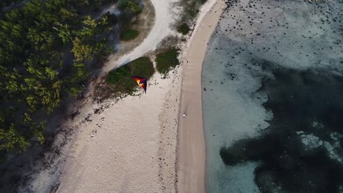 Top-down aerial view of a colorful kite on a sandy peninsula in Mauritius. Concept of freedom