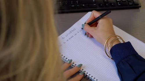 Young Adult Writes in Notebook in Office