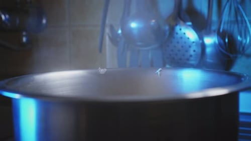 Close Up of a Large Pot Boiling and Steaming in a Dark Kitchen