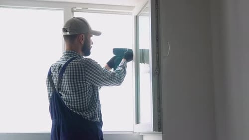 Man in Uniform Does Pvc Window Installation with a Screwdriver