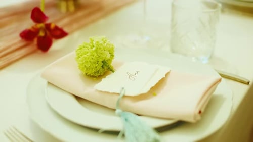 Slow Slider Shot of a Elegant Wedding Table Place Setting with Handwritten Name Card and Flower in a