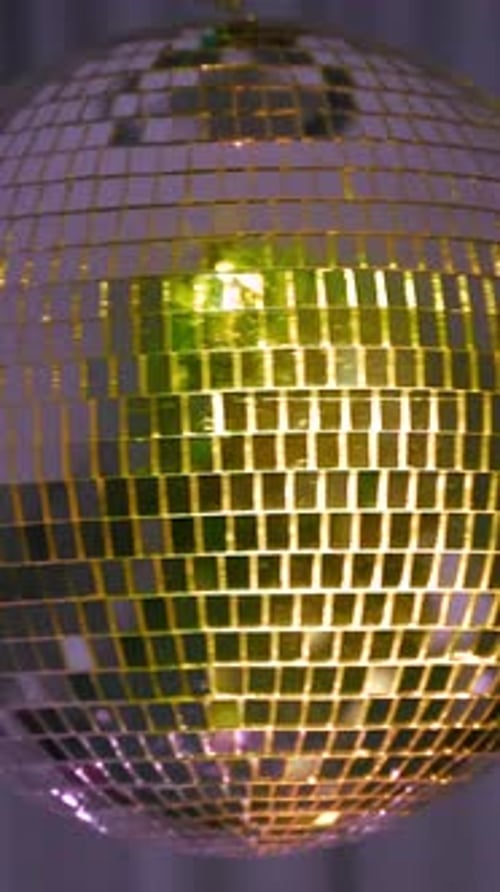Sparkling disco ball reflects colorful lights. Vertical