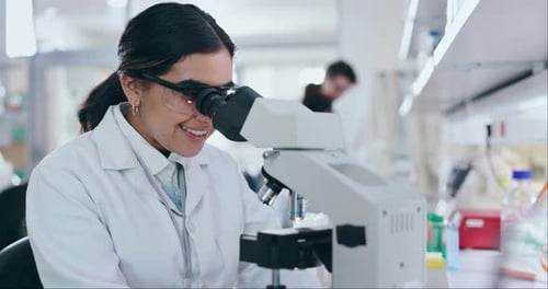 Young Woman Smiling Using Microscope in Modern Lab