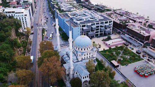 Aerial view of Dolmabahçe Mosque with its elegant domes and minarets beside modern buildings near