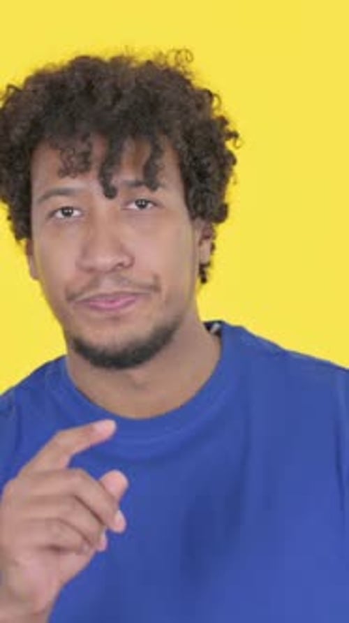 Hombre africano apuntando a la cámara sobre fondo amarillo, Vídeo vertical