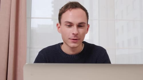 Young Man Talking on Laptop in Bright Room