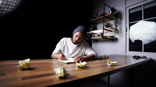 Disappointed caucasian male tearing out a page from his notebook sourrounded by crumpled ball of pap