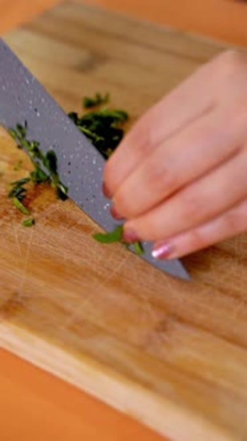 Hands Chopping Fresh Parsley on Wooden Cutting Board