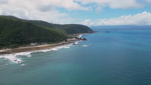 A stunning shot showcases lush green landscapes meeting the tranquil shoreline, with the vast ocean