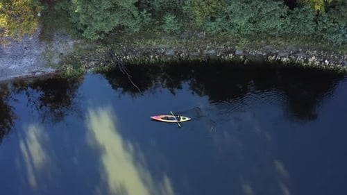 Man in a Kayak or Kayak Floats on a Lake Near the Shore With Trees Top View