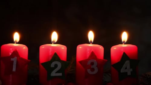 New Year and Christmas Preparation Four Red Advent Candles with Numbers Burning in Dark Background