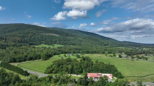 Aerial View of Cars Traveling Along a Rural Road Through Lush Green Farmlands