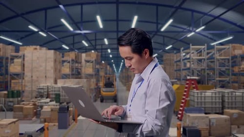 Asia Male Worker Is Typing Laptop in Warehouse