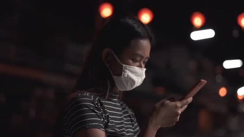 Girl wearing mask during corona virus pandemic and using phone on empty chinese street