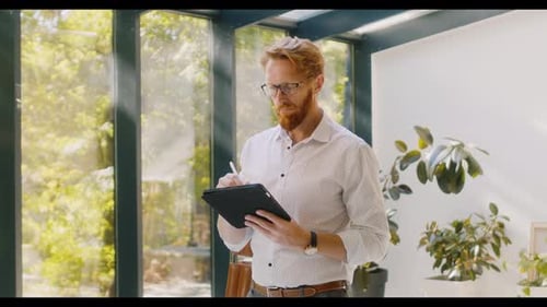 Man with Tablet Writing Near Glass Window