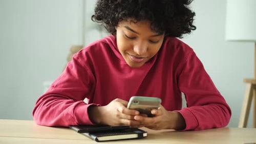 Young Adult Uses Smartphone at Table Indoors