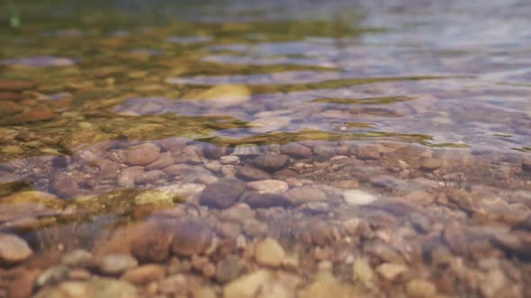 Rocks are visible below the clear water of a river. Shallow river shore ...