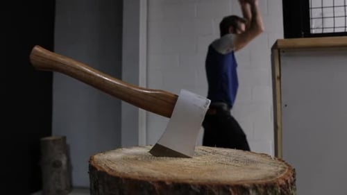 Axe on a Log While Man Throws Axe in Axe Throwing Arena