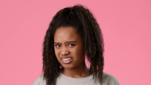 Teen Girl Expressing Confusion Against a Vibrant Pink Background