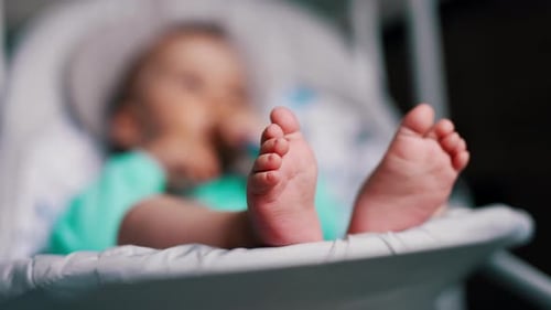 Beautiful tiny baby feet. Close up. Adorable child sitting in a rocking chair peacefully.