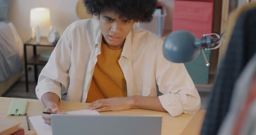 Young Adult Studying at Desk in Bedroom