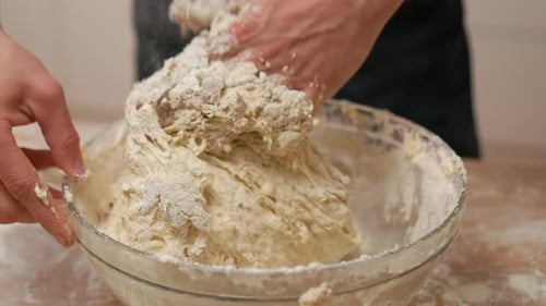 Hands Mixing Dough in Bowl on Wooden Table
