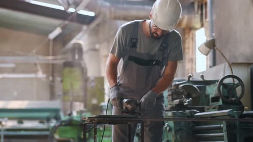 Ein Arbeiter in einer Schwerindustriefabrik für die Herstellung von Metallkonstruktionen. Ein Mann in einem einheitlichen Grinsen