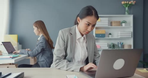 Asia businesswomen using laptop on table working and communicate sitting on office desk.