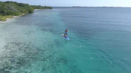 Aerial view of young couple stand up paddling on vacation of carenero island near blue waters Los Ro