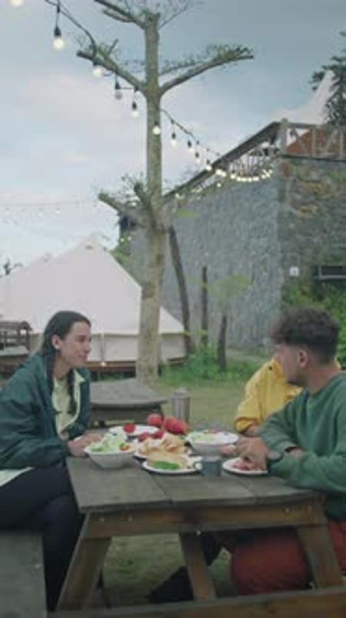 Friends Eating Meal While Camping Outdoors