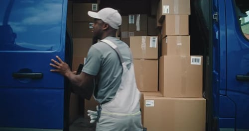 Employee Opening Door of Delivery Truck Using Digital Tablet Unloading Cardboard Boxes