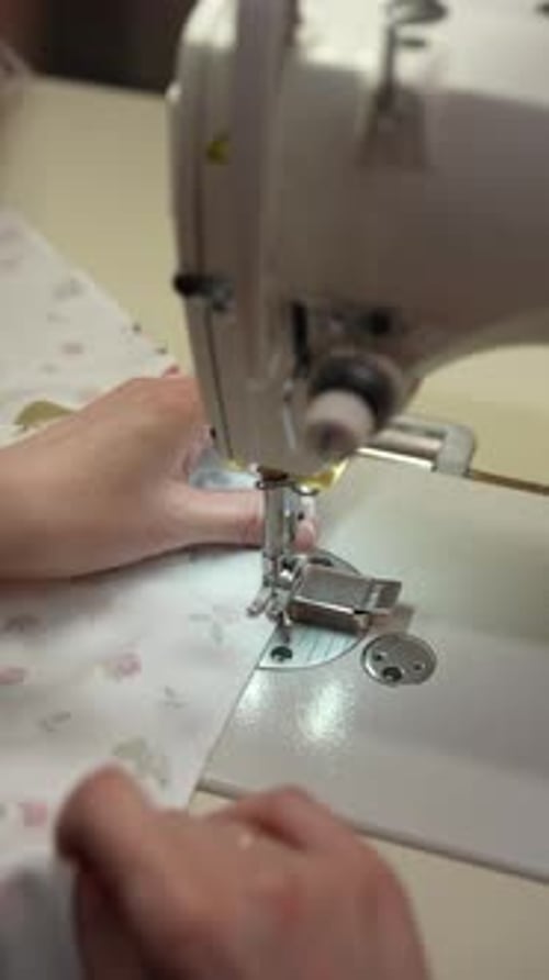 Seamstress Using Sewing Machine Focusing on Fabric Alignment and Stitching in Fabric Workshop